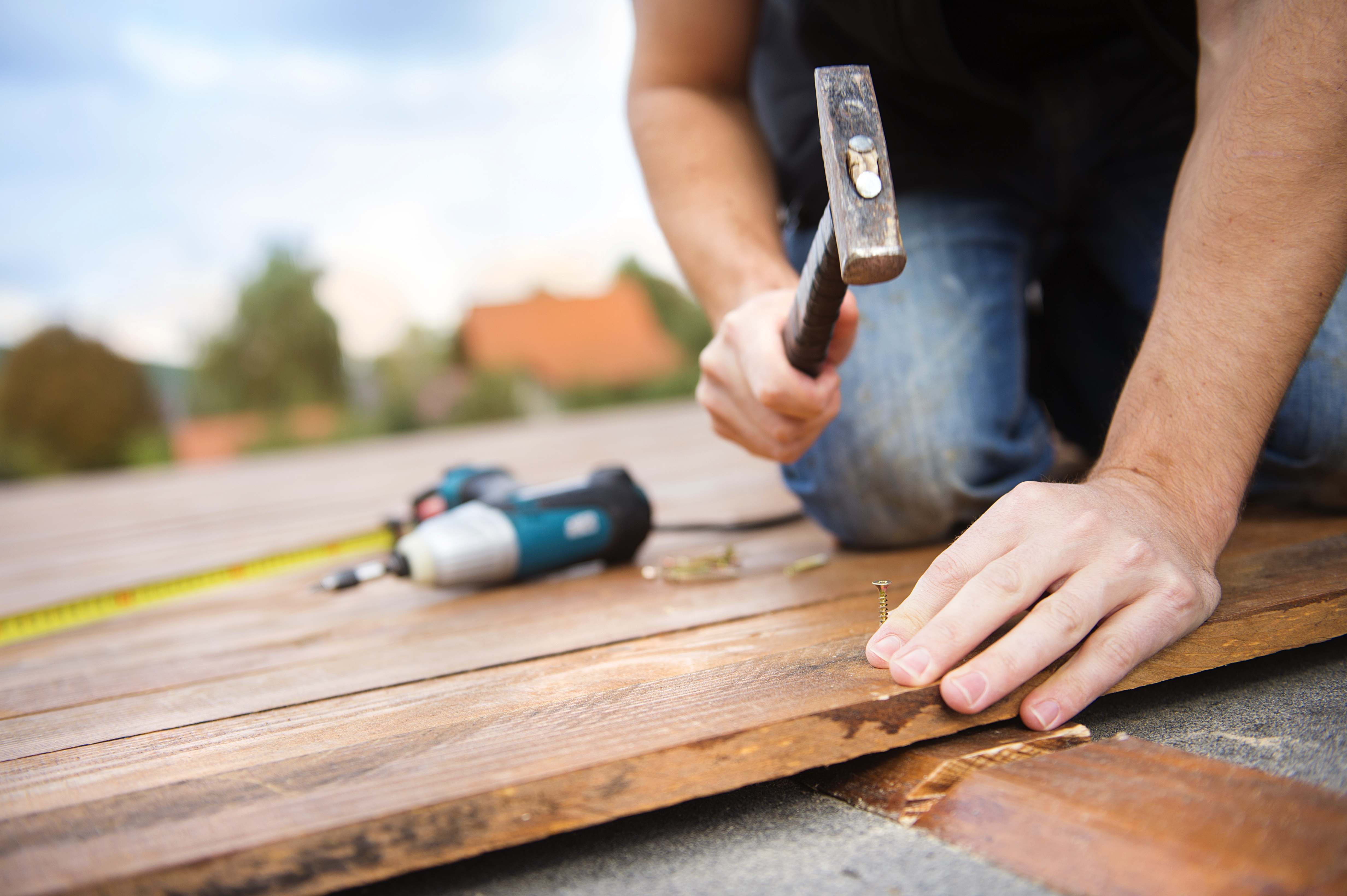 Worker hammering nail into wooden floorboard during installation project